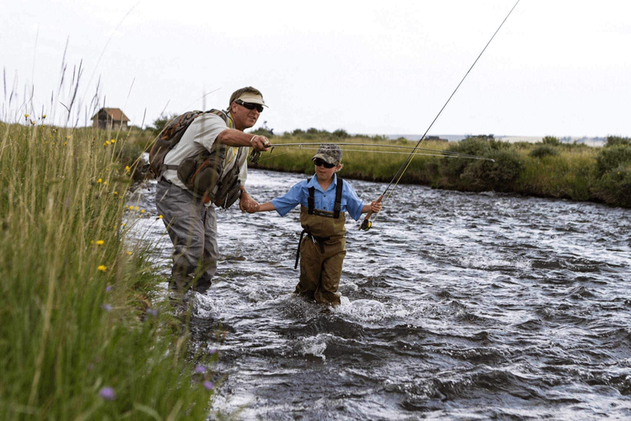A father holds his son hand while teaching him to fly fish in Breckenridge, Colorado. Fly fishing is one of the most popular outdoor activities in Breckenridge.