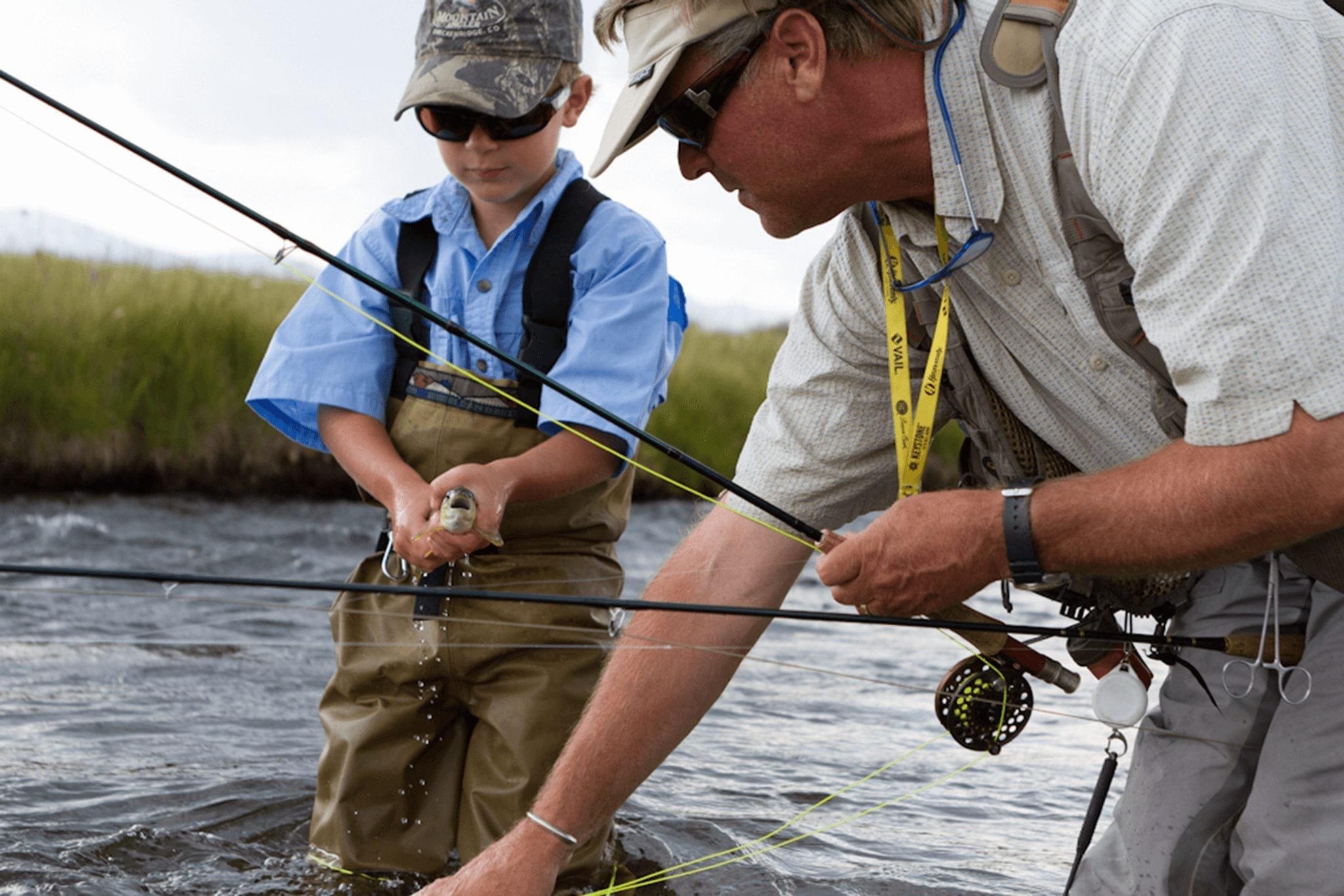 A son holds his catch with his father in the Blue River